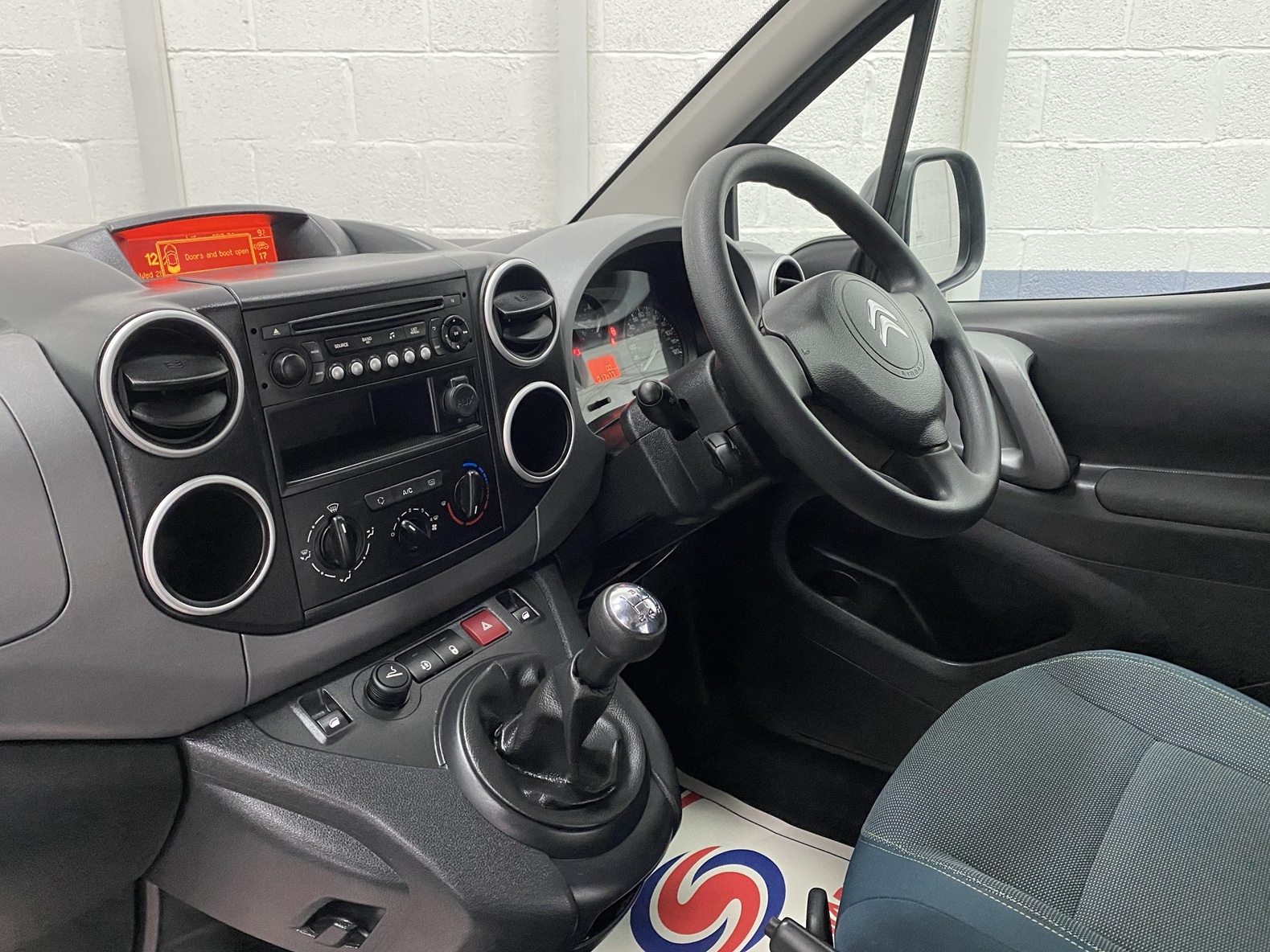The central dashboard controls and steering wheel on a wheelchair accessible Citroen Berlingo that is for sale at Michael Harraway Cars NK68 AYF 14