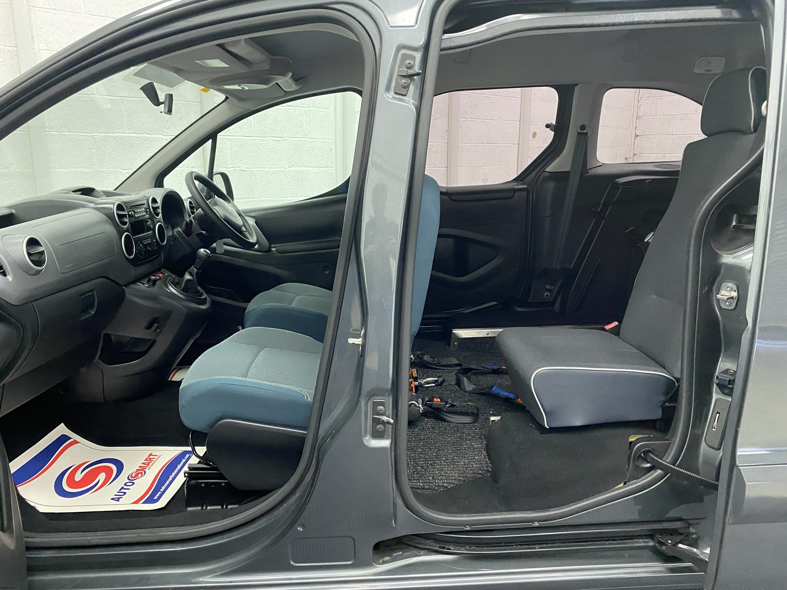 The side view of a Wheelchair accessible Citroen Berlingo with the front doors open showing the interior Nk68 AYF