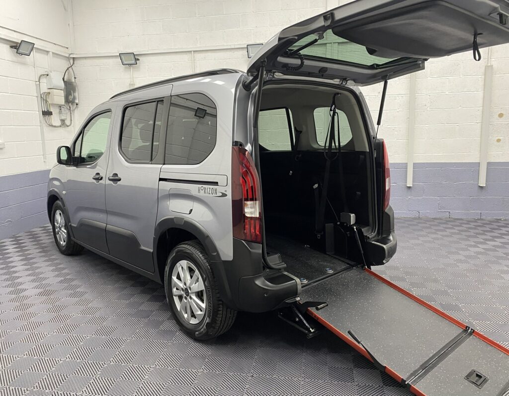 2025 A wheelchair accessible Peugeot Rifter with the rear ramp deployed and nearside three quarter view SC74 XAO